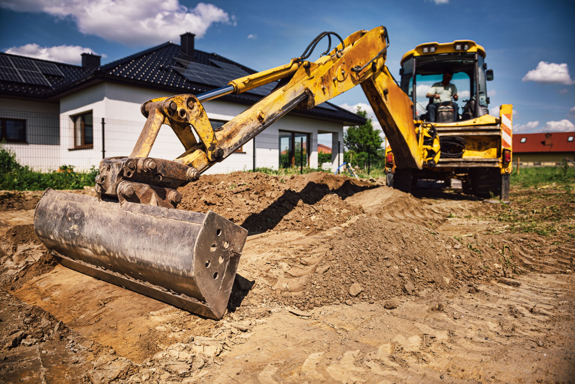 Gelber Minibagger bei Erdarbeiten für den Neubau eines Einfamilienhauses. Aushub für Fundament ist sichtbar.