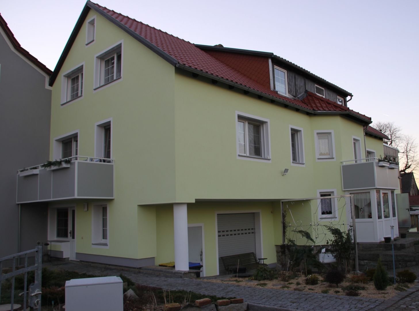 Referenz - Hochbau - Gelb/Grünes Mehrfamilienhaus mit einer Garage und mehreren Balkons