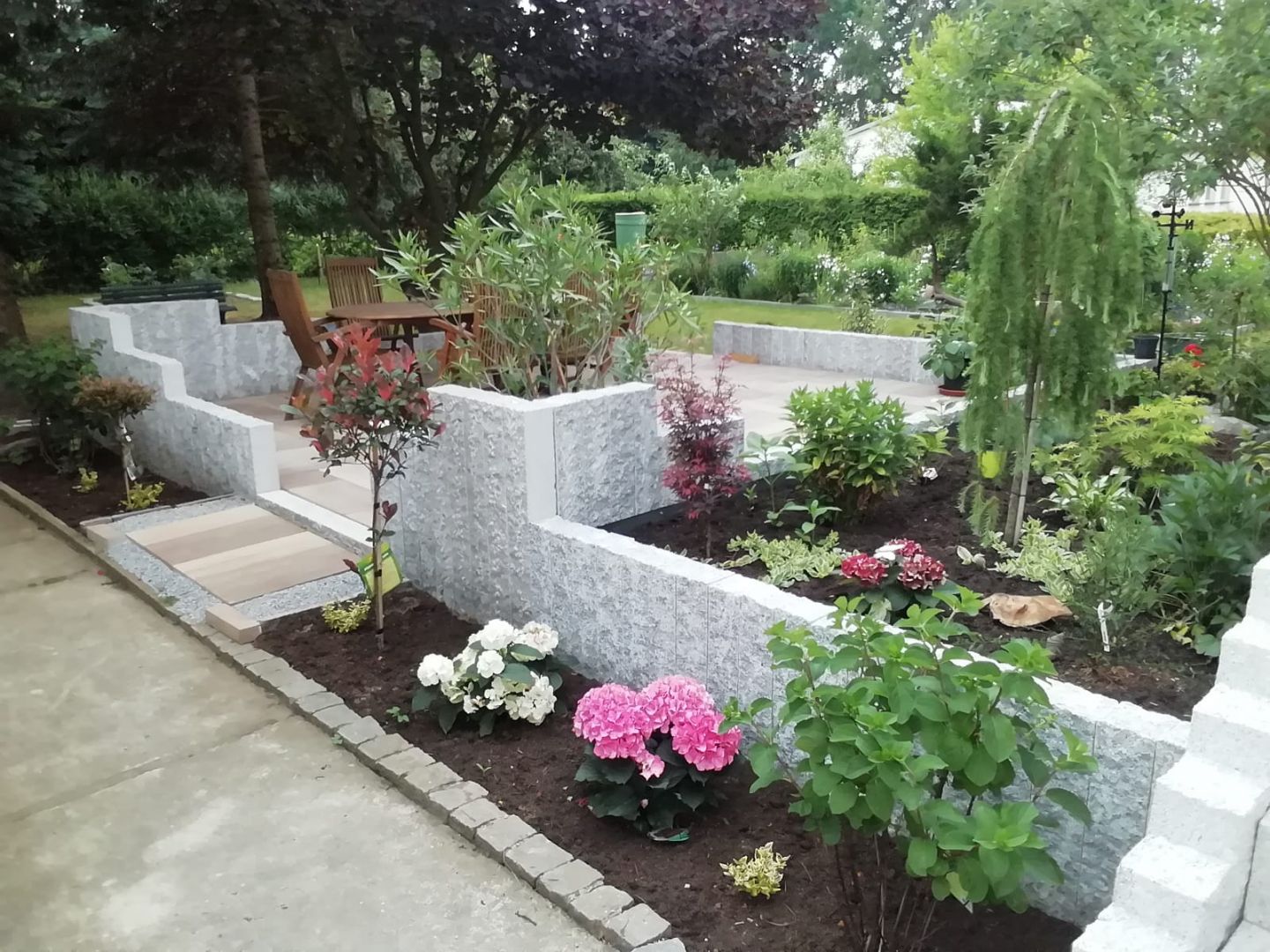 Gartengestaltung mit Terrassierung durch Natursteinmauern und vielfältiger Bepflanzung in einem Garten in Bautzen.