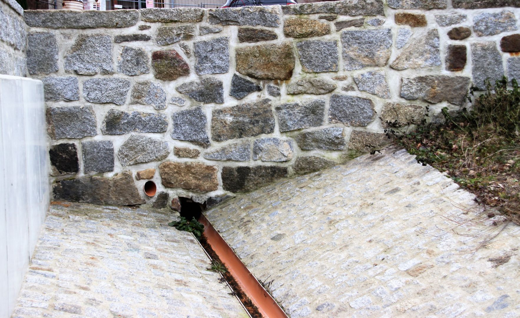 Trockenlegung einer Natursteinmauer mit Drainageleitung und Schotter, Sanierungsarbeiten in Bautzen.
